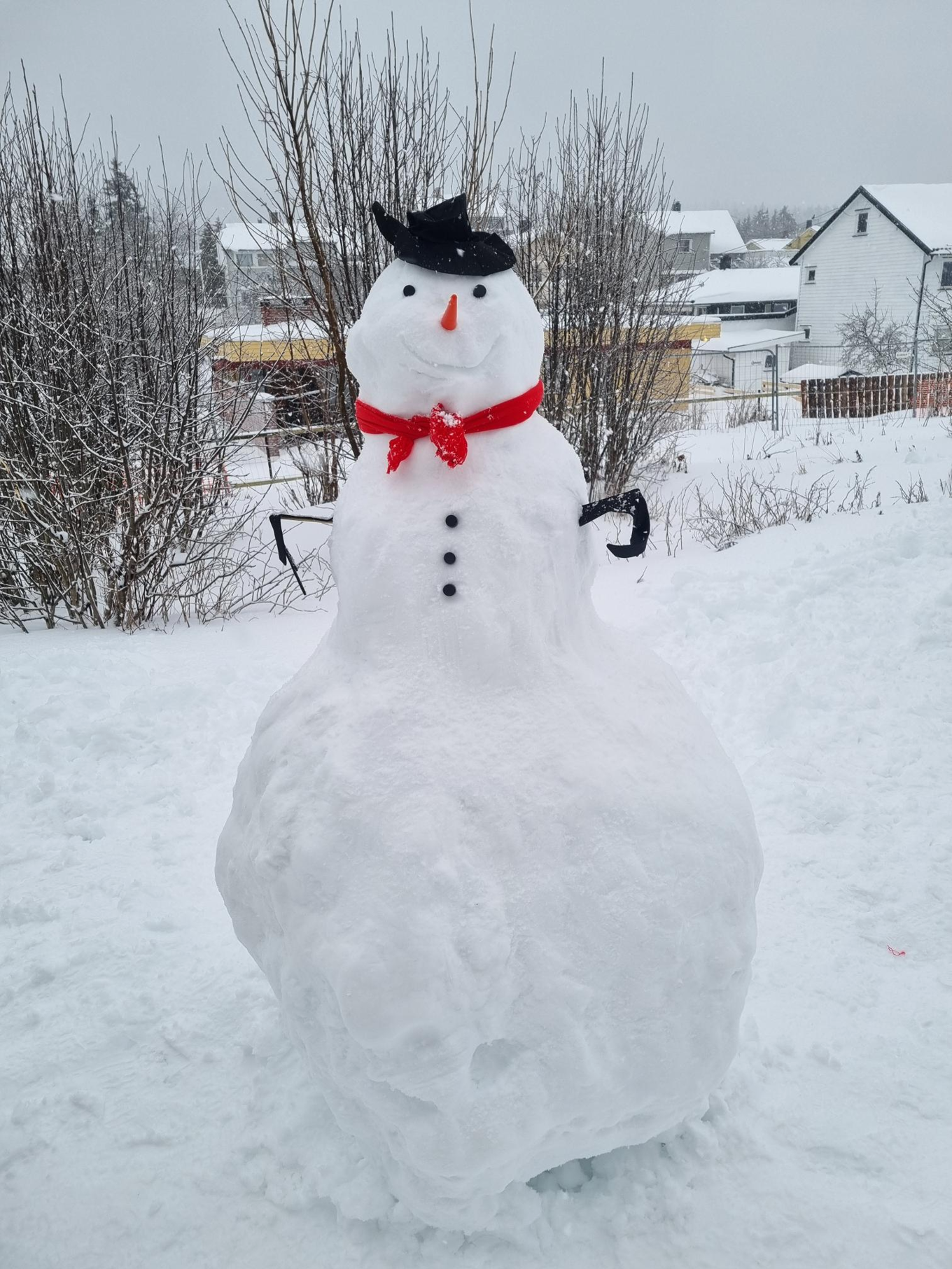 En snøperson med hatt og rødt skjerf