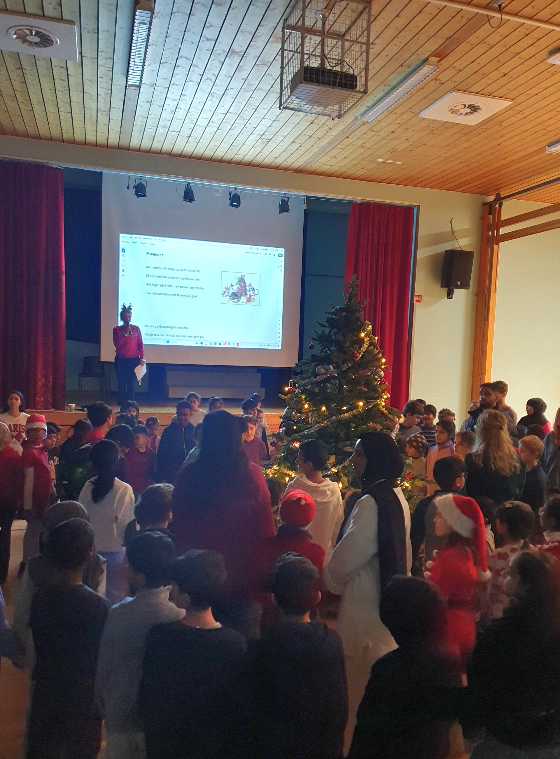 Elever og ansatte går rundt juletreet og synger julesanger